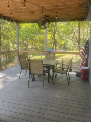 Un patio coperto con tavolo e sedie, una ventola e una bandiera americana.