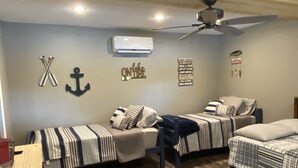 Ein Schlafzimmer mit zwei Einzelbetten, einem Schreibtisch und einem Deckenventilator.