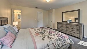 Un dormitorio con cama, cómoda y un espejo grande.