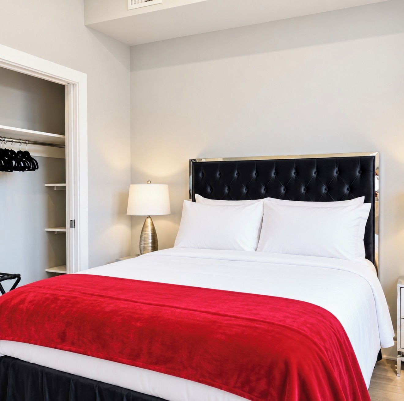 A hotel room with a bed, a nightstand, a lamp, and a closet.