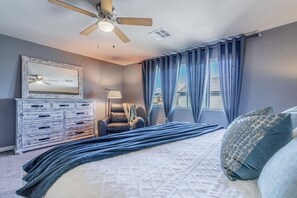 A bedroom with a bed, a ceiling fan, a dresser, a chair, and a window with curtains. - Inviting Sunny House! Poker table~ 4br 3ba 7 beds/ 10 mins to Airport & Strip! (Las Vegas)