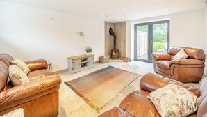 A modern living room with leather sofas, a wooden cabinet, and a fireplace.