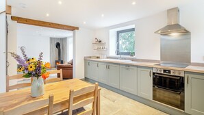 A modern kitchen with a built-in stove, a window, and a dining area with a wooden table and chairs.