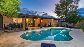 Ein Garten mit Swimmingpool, einer Terrasse mit Sitzgelegenheiten und einem Ziegelhaus.