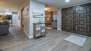 Ein geräumiger Wohnbereich mit grauem Sofa, einem Holzkabinett und einem gemusterten Teppich.