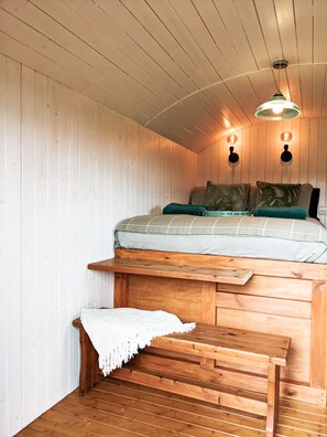 A cozy wooden cabin room with a bunk bed, a small bench, and a ceiling light fixture. - Stunning Shepherd's Hut Retreat, North Devon (Bideford)
