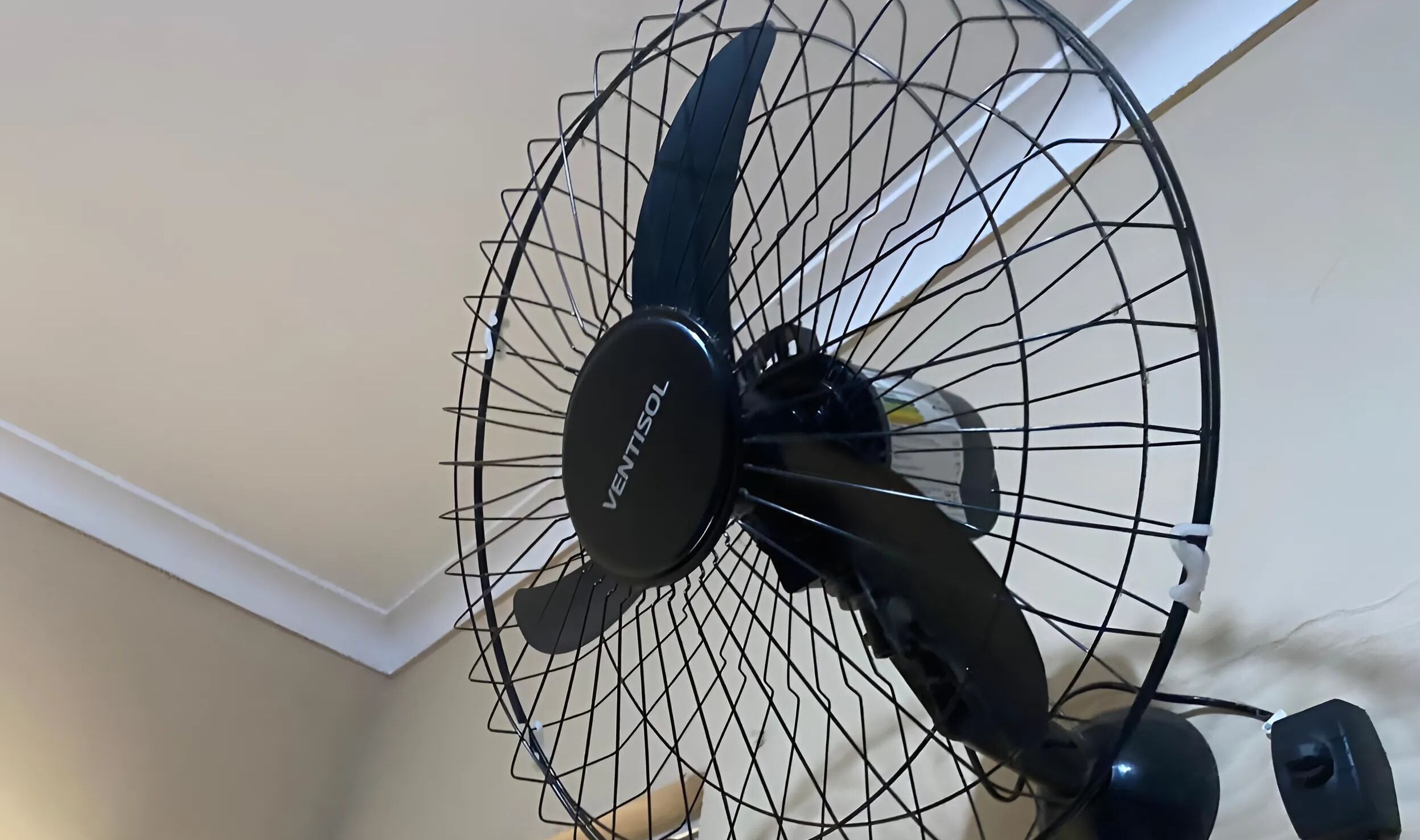 Un ventilateur de plafond doté d’une grille de protection et d’une marque clairement visible.