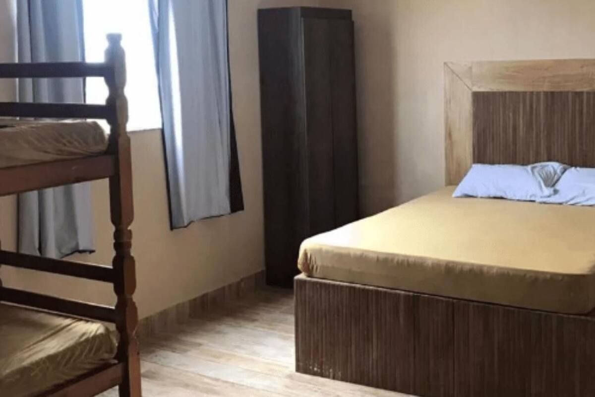 A small, simple room with a bed, a chair, and a tall cabinet.