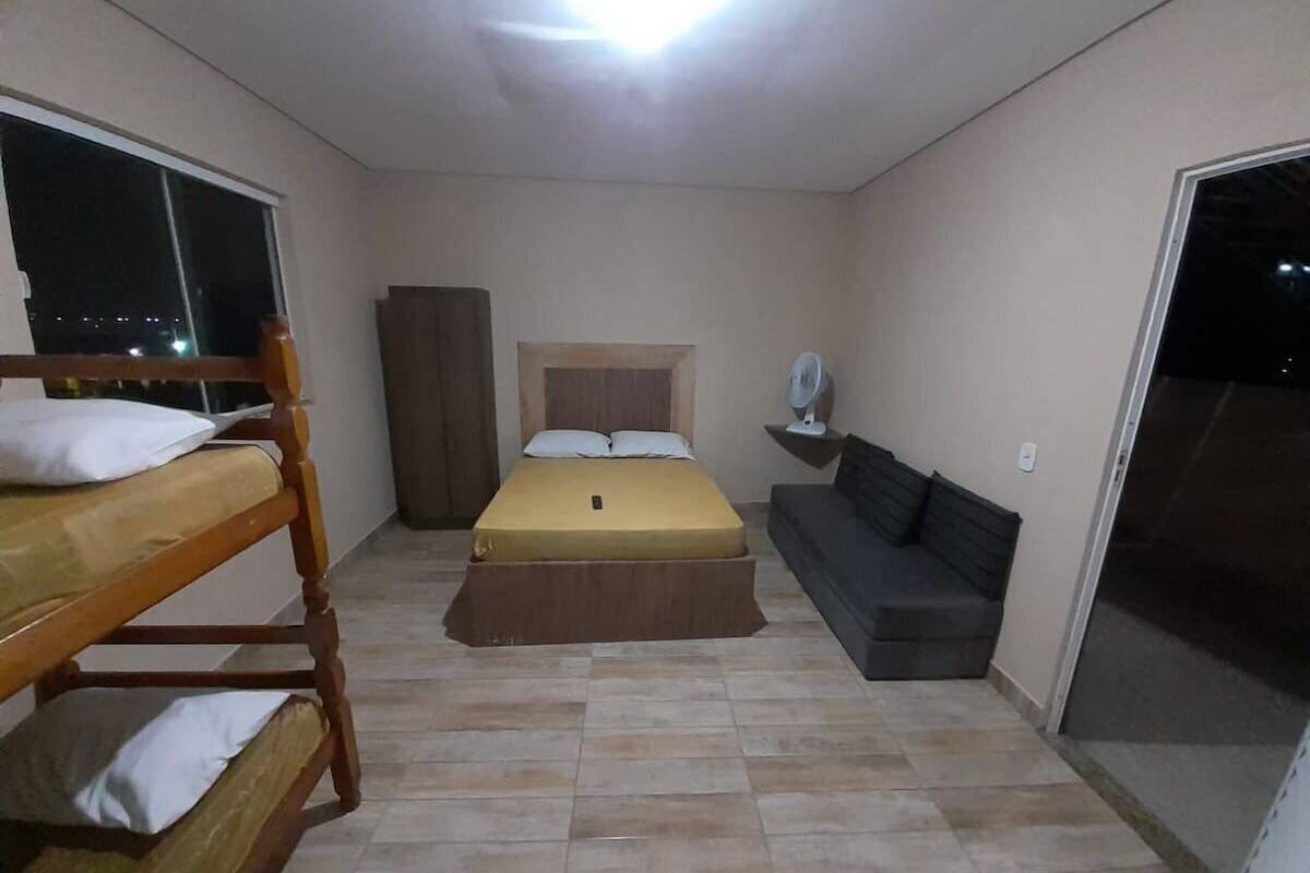 A compact room with a bunk bed, a single bed, a sofa, and a small table.