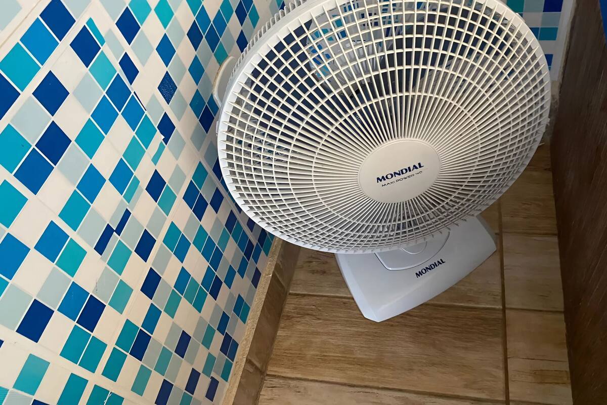 A white MONDIAL MAXX fan in a bathroom with blue and white checkered tiles.