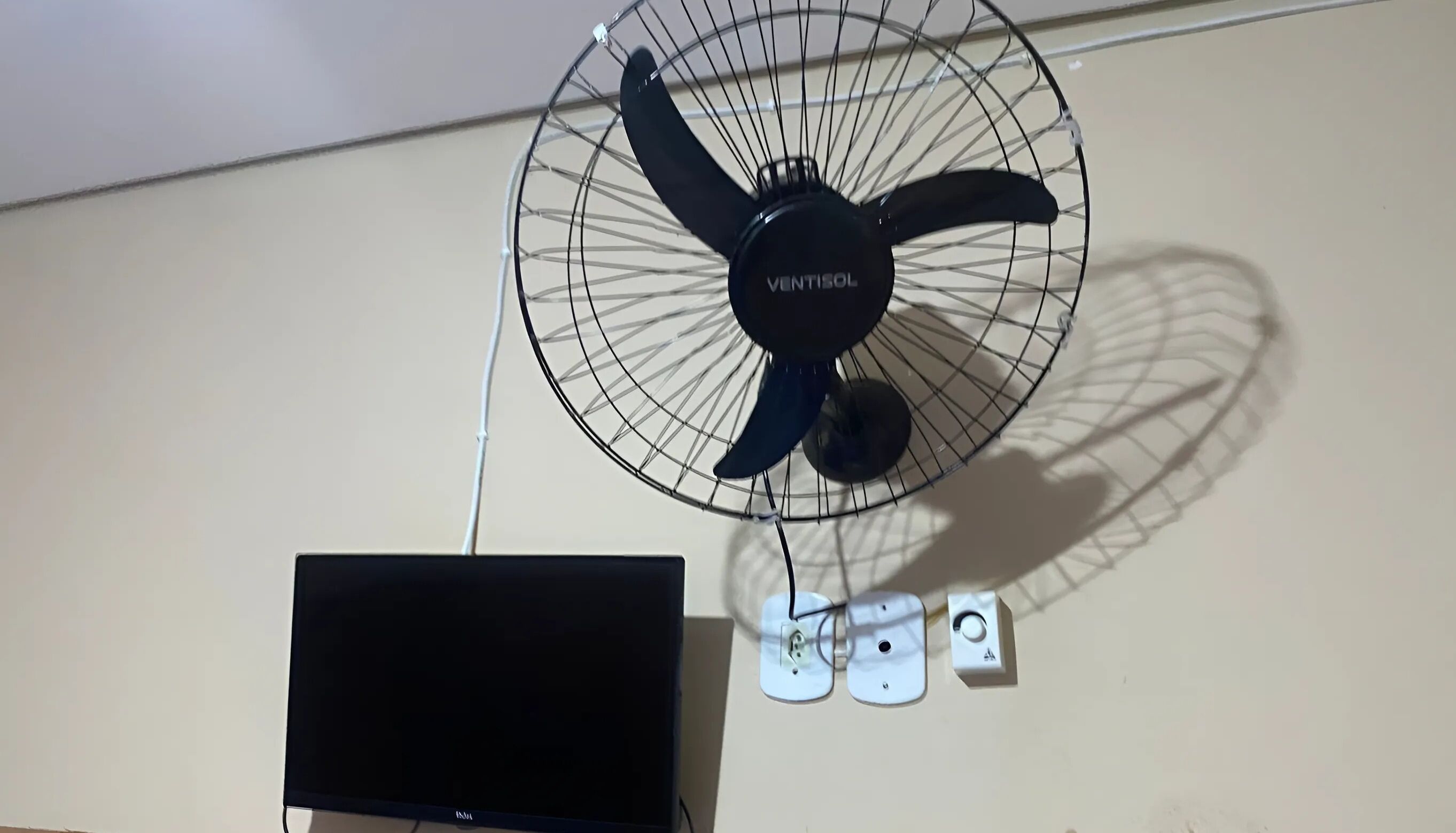 A wall-mounted fan with the brand name 'VENTISOL' and a flat-screen TV below it.