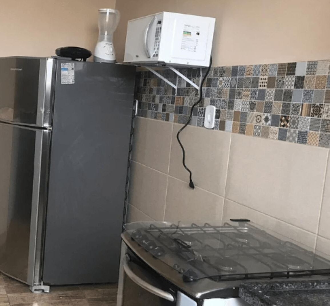Een keuken met een koelkast, een magnetron en een gasfornuis.