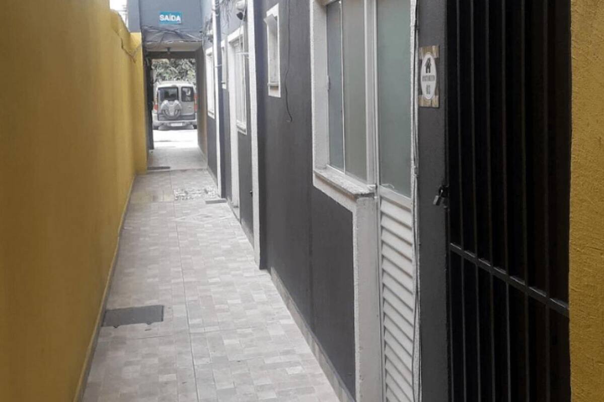 A narrow corridor with a tiled floor, a yellow wall on the left, and a black gate on the right.