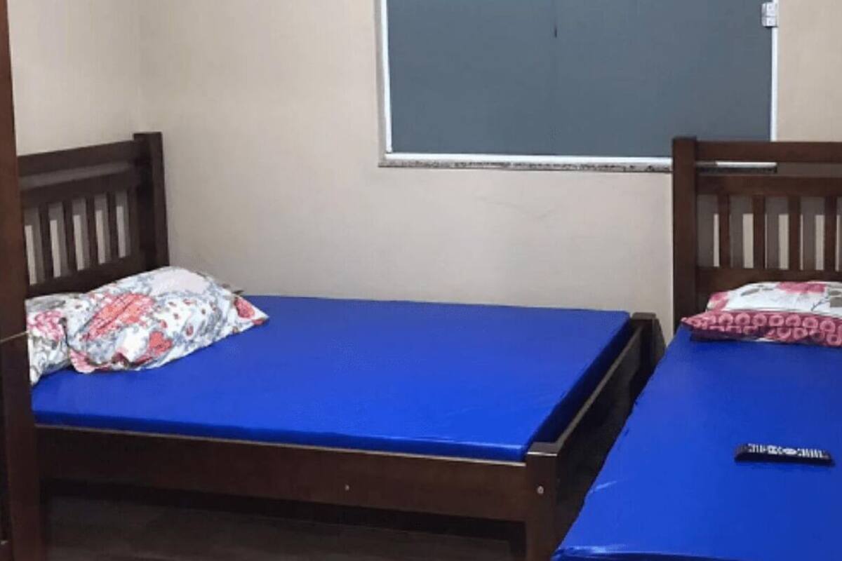A small room with two wooden bunk beds, each with a blue mattress and floral-patterned pillows.