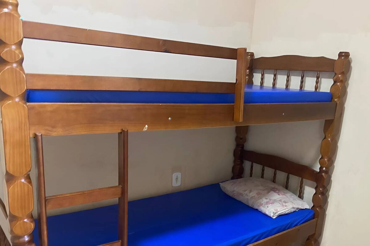 A bunk bed with a blue mattress and a pillow.