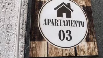 Ein Schild mit einem Haus-Symbol und dem Text 'APARTAMENTO 03' auf Holz.