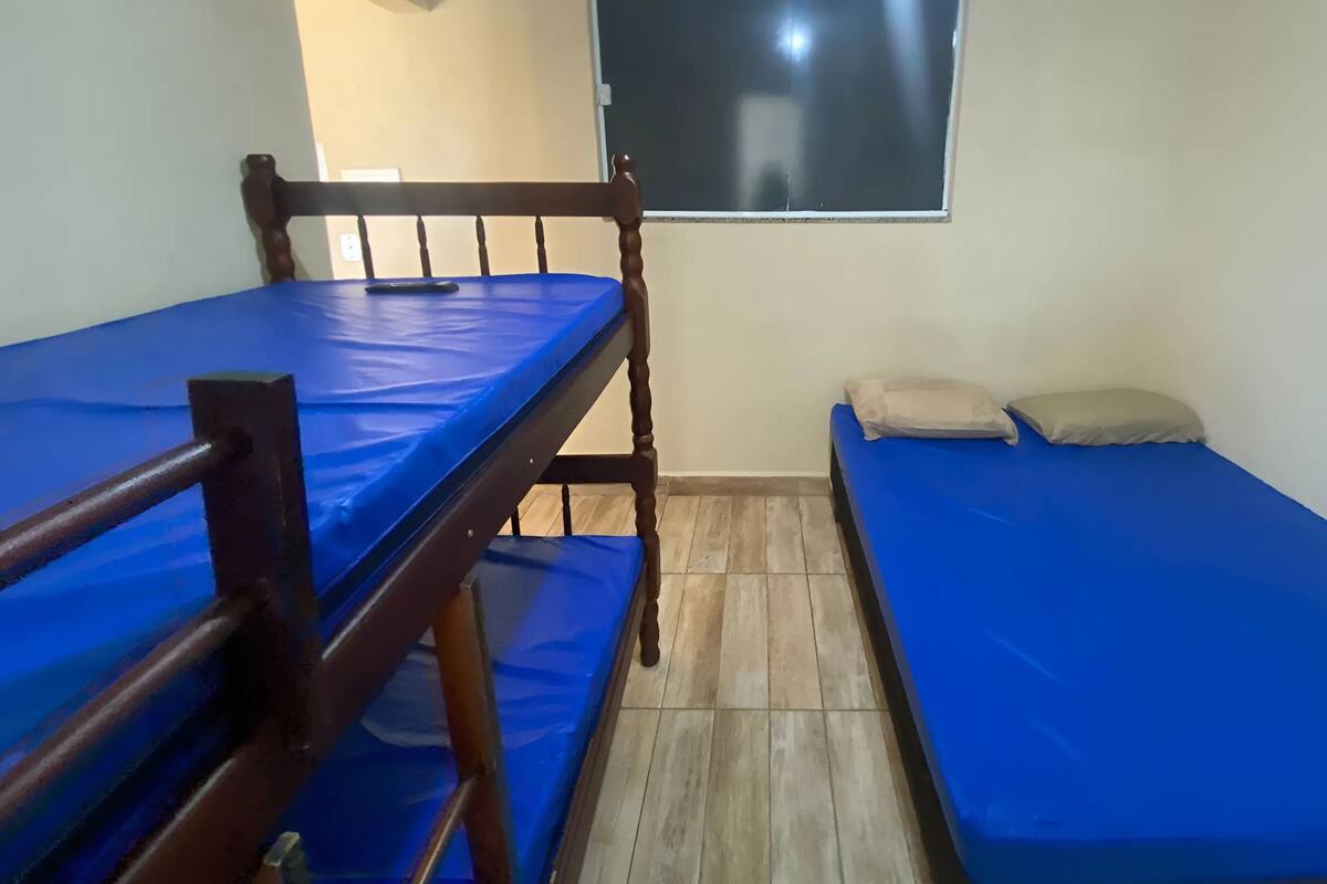 A room with two bunk beds, a small table, a window, and a wall-mounted blackboard.