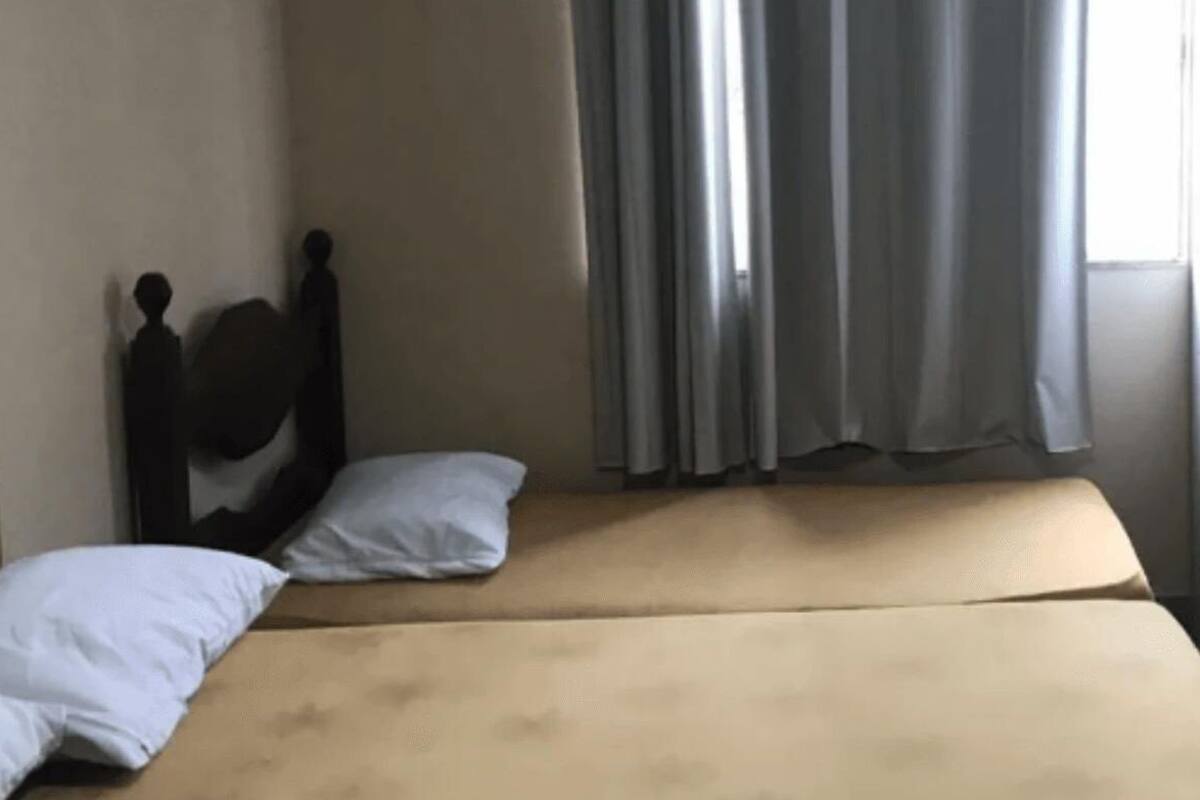A room with a bed, a wardrobe, and a window with curtains.
