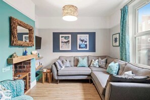 A cozy living room with a sectional sofa, a fireplace, and artwork on the walls. - Chic 3BR Stylish House, Central & great for groups (Portsmouth)
