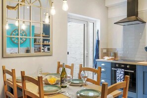A kitchen with a dining table set for four, a stove, and a large window. - Chic 3BR Stylish House, Central & great for groups (Portsmouth)