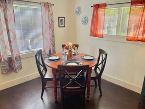 Un comedor con una mesa redonda de madera dispuesta para cuatro personas, rodeada por cuatro sillas.