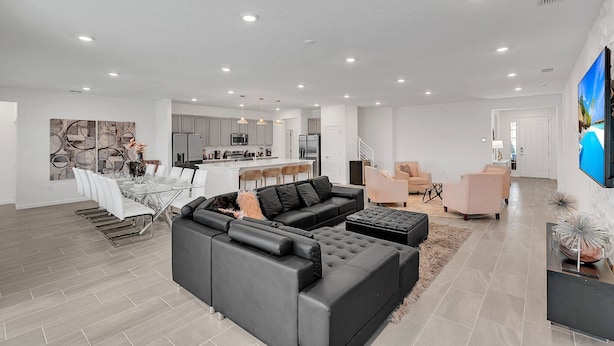 Amplia sala de estar con sofá modular, mesa de comedor y cocina al fondo.