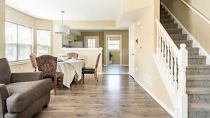 A spacious living area with a dining table, chairs, and a staircase.