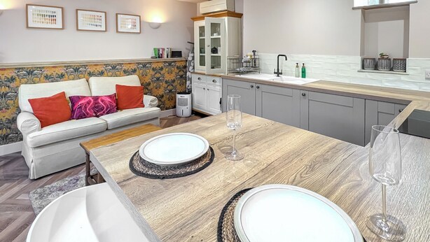 Una cocina moderna con una mesa de comedor de madera, un horno empotrado y un lavamanos blanco.