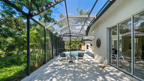 A covered outdoor area with a pool, lounge chairs, and a glass-enclosed patio. - Sea Glass Serenity, 3+2, Nokomis Beach, Heated Pool (Nokomis)