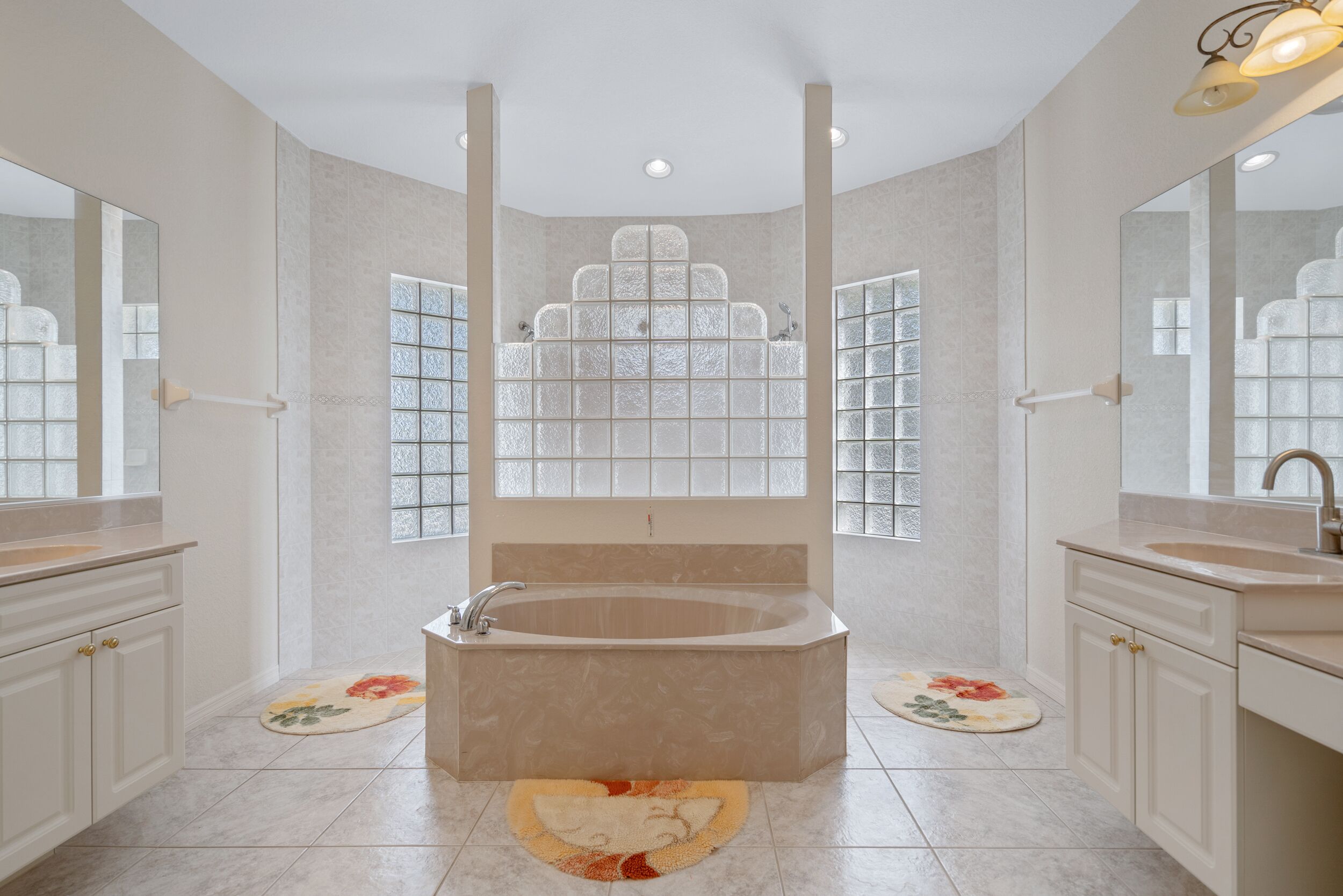 Een moderne badkamer met een vrijstaand bad, twee wastafels en een grote spiegel.