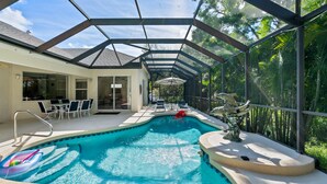 An indoor swimming pool with a glass ceiling, surrounded by chairs and a statue. - Sea Glass Serenity, 3+2, Nokomis Beach, Heated Pool (Nokomis)