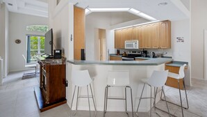 A modern kitchen with a central island, wooden cabinets, and a large window. - Sea Glass Serenity, 3+2, Nokomis Beach, Heated Pool (Nokomis)