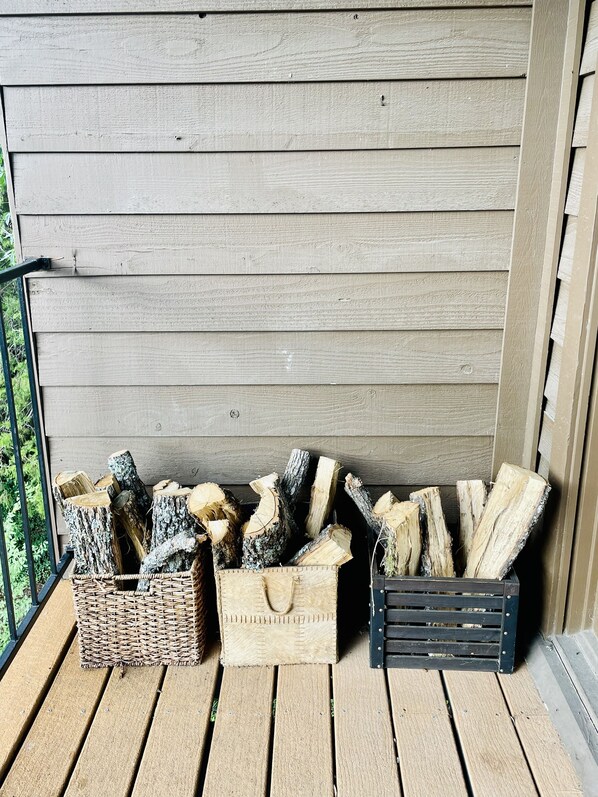 A wooden deck with firewood stacked in baskets and crates.