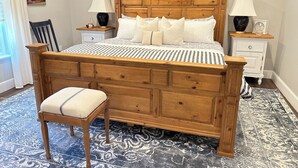 A bedroom with a wooden bed, two bedside tables, a chair, and a patterned rug. - Guest Apartment close to Ski Resorts, Hiking Trails, Shopping Restaurants & more (Holladay)