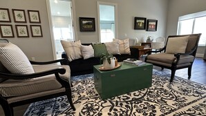 A living room with a dark sofa, striped armchairs, a green coffee table, and a patterned rug. - Guest Apartment close to Ski Resorts, Hiking Trails, Shopping Restaurants & more (Holladay)
