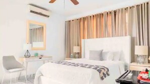 Quarto de hotel com cama, escrivaninha, cadeira e cortinas.