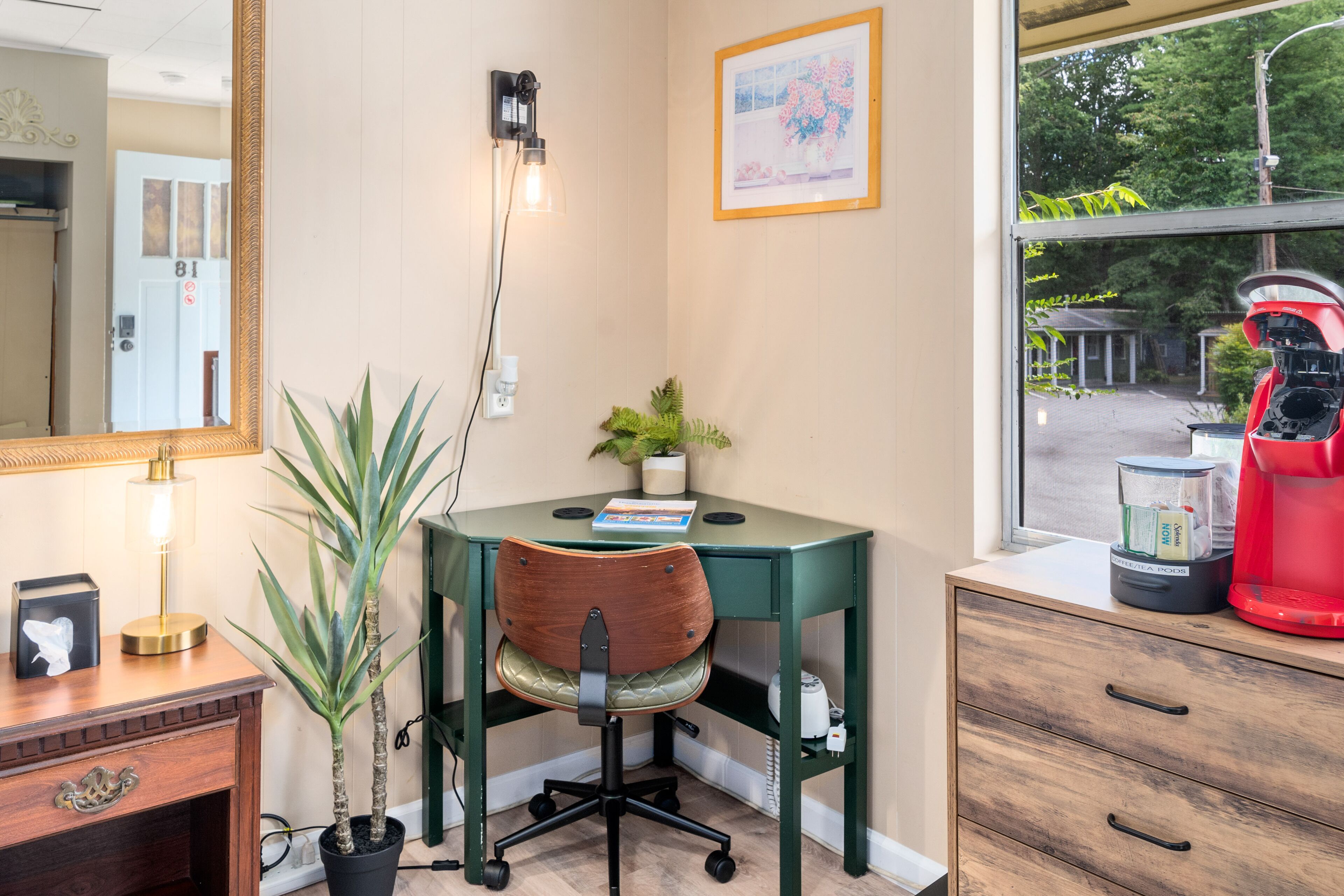 A small office space with a desk, chair, and a window with a view of trees.