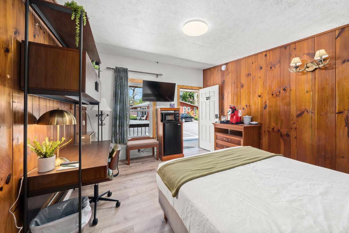 A compact hotel room with a bed, desk, chair, and a TV.