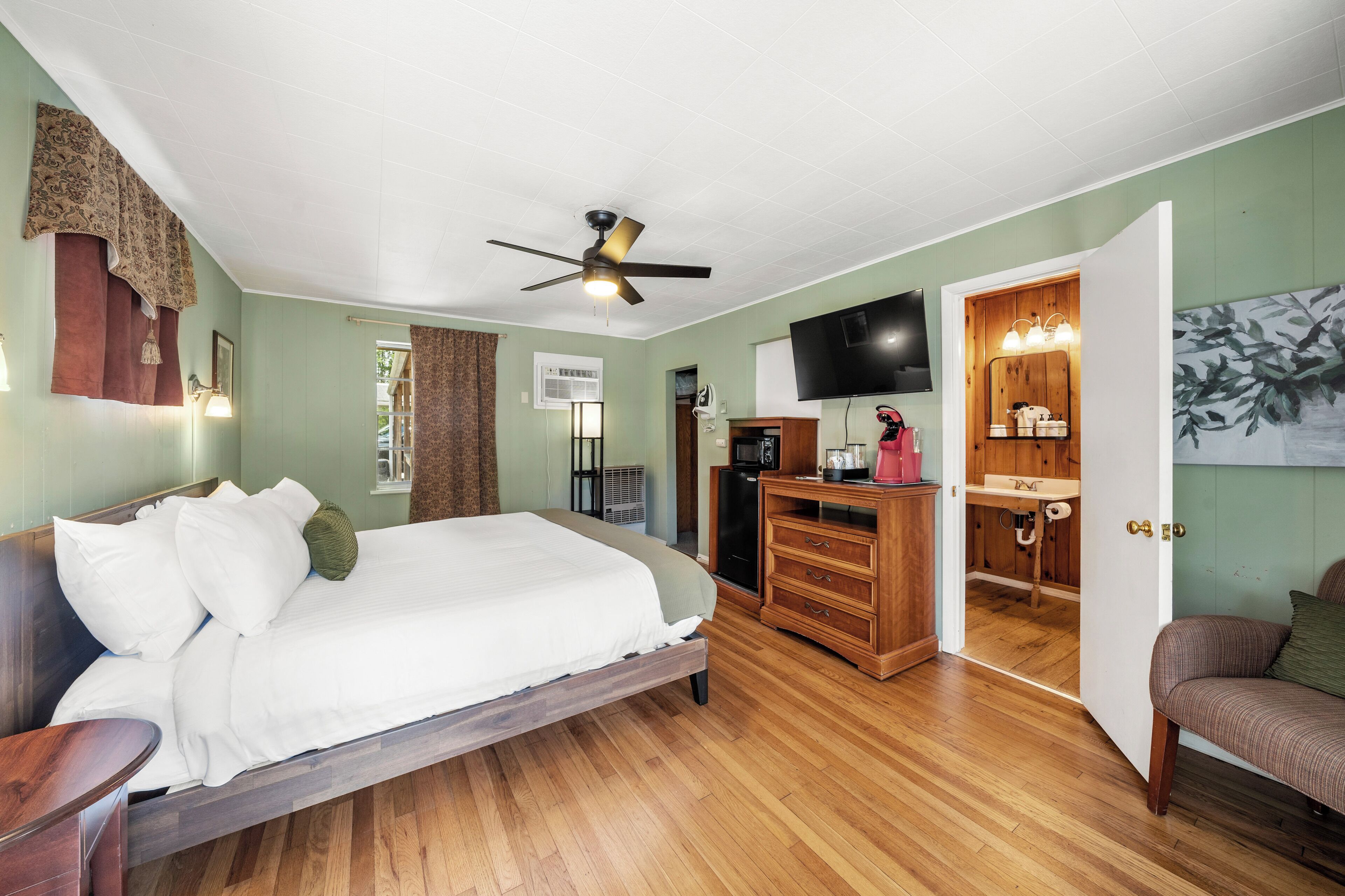 Une chambre à coucher avec un lit, une commode en bois et un téléviseur.