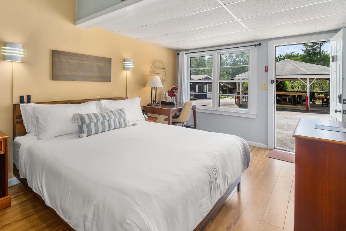 A neatly arranged bedroom with a large bed, bedside tables, and a view through a glass door to an outdoor area.