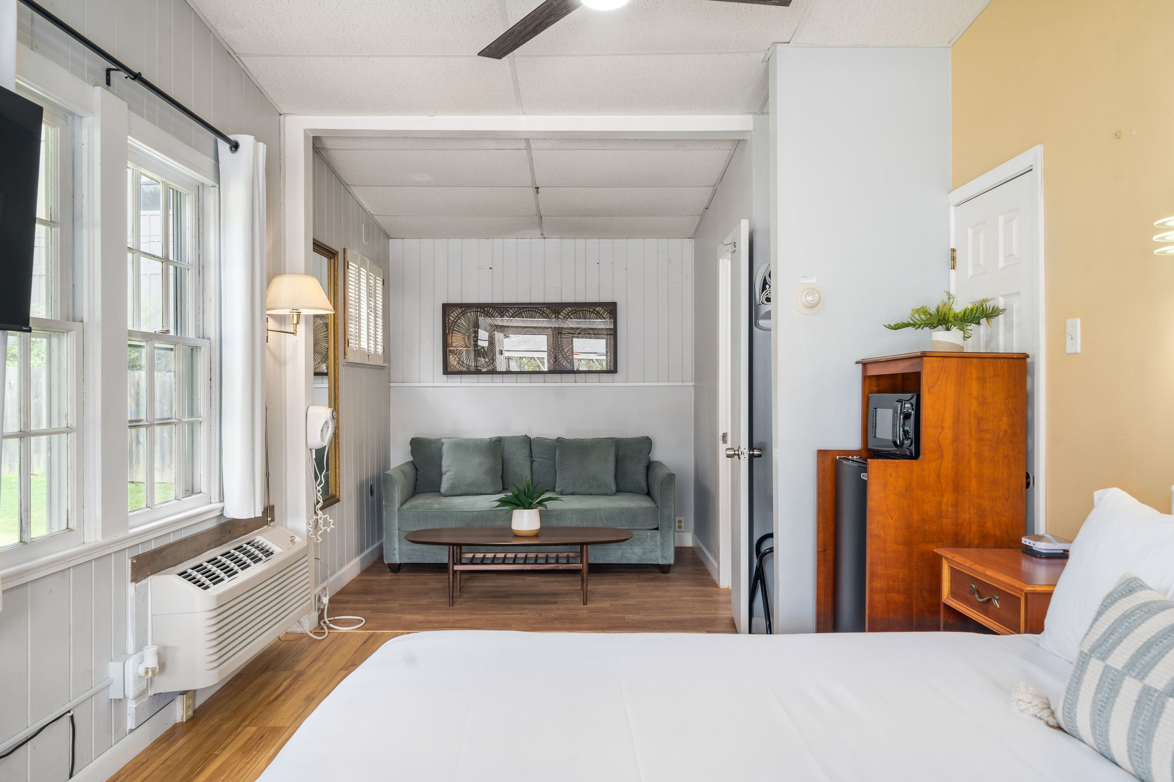 A room with a bed, a sofa, a coffee table, a heater, and a small cabinet.