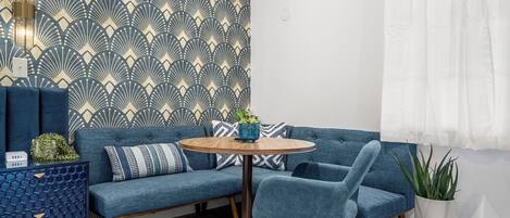 Ein modernes Wohnzimmer mit einem blauen Sofa, einem runden Holztisch und einer Wand mit Muster.
