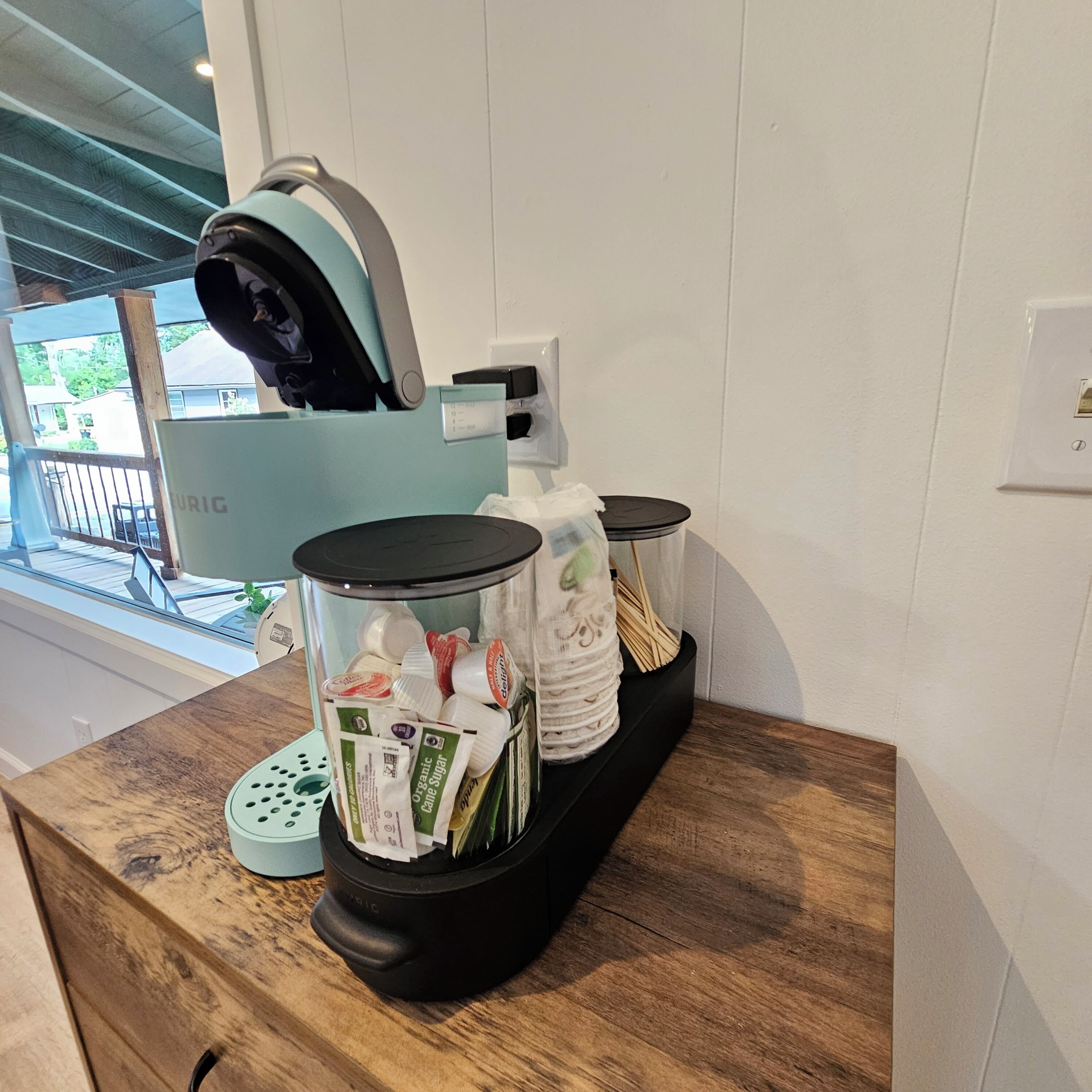 A coffee station with a coffee machine, a milk frother, and a dispenser of organic cane sugar.