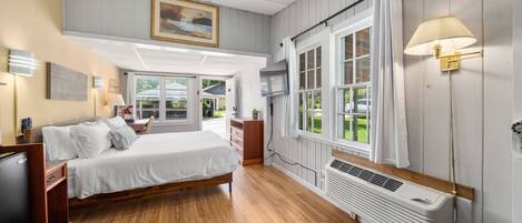 A bedroom with a bed, bedside table, lamp, and a window with curtains.