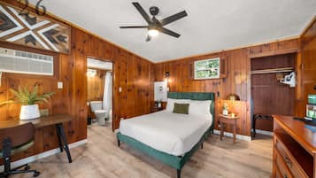 Un dormitorio con cama, escritorio, silla y ventilador de techo.