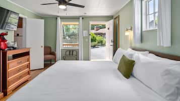 Une chambre à coucher comprenant un lit, une commode, une chaise et une porte donnant sur l’extérieur.