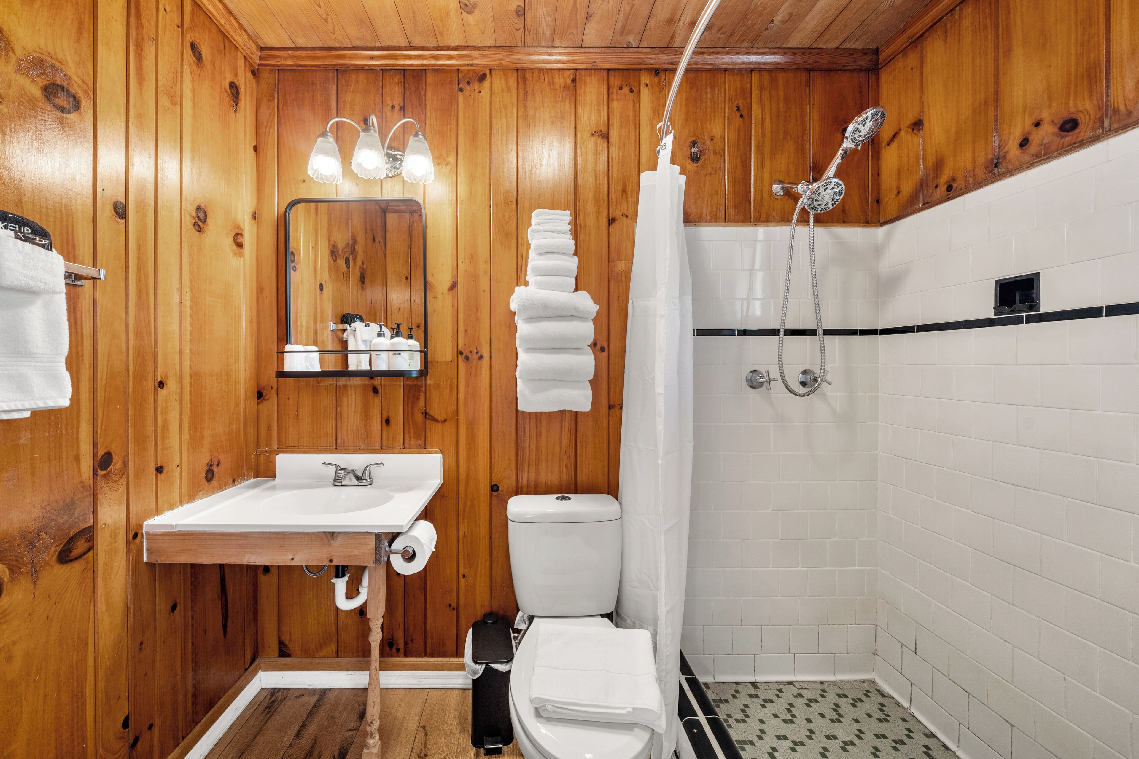 A wooden-paneled bathroom with a sink, toilet, and shower.