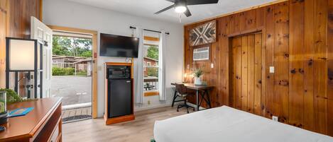A hotel room with a bed, desk, chair, and a television.