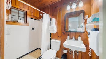 A wooden-paneled bathroom with a toilet, sink, and mirror.