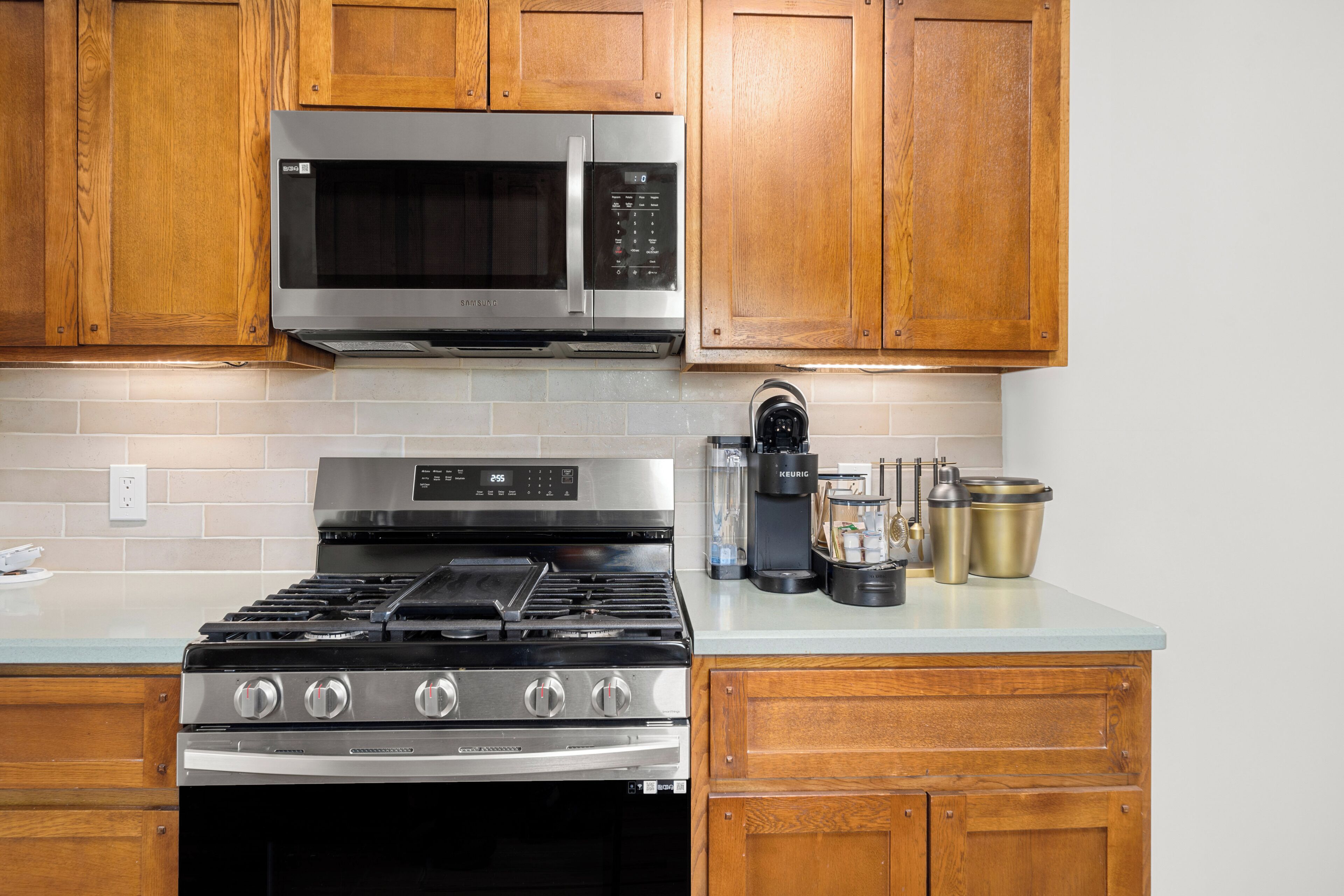 A kitchen with wooden cabinets, a stainless steel microwave, a gas stove, and a coffee maker.